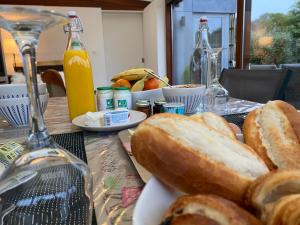 La couette du voyageur في Wanze: طاولة مع صحن من الخبز وزجاجات من عصير البرتقال