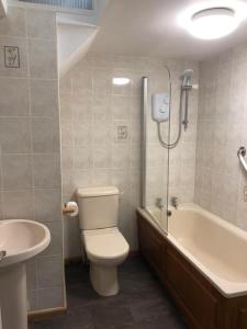 a bathroom with a toilet and a tub and a sink at Harbourside Apartment in the centre of Looe in Looe
