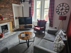 a living room with a couch and a tv at Snug - Abhainn Apartment in Helensburgh