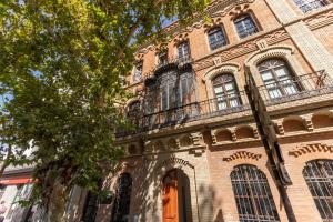 a large brick building with windows and a balcony at Charming 2 Bedroom Apartment at Sevilla City Center By Cityzen in Seville