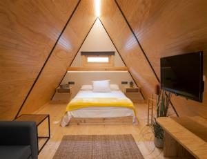 1 dormitorio con 1 cama y TV en una habitación en Glamping -Bungalows El Faro, en Conil de la Frontera