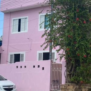 a pink house with a fence and a tree at Pousada Aquarela in São Thomé das Letras