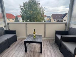 een balkon met een tafel en een fles wijn bij Ferienwohnung Frühauf Rochlitz in Rochlitz
