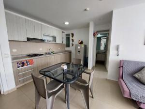 a kitchen and dining room with a glass table and chairs at Aqualina Orange Hermoso Apartamento Piso 3 Vista a Piscina in Girardot