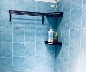 a blue tiled bathroom with a bottle of soap on a shelf at SOFEA HOMESTAY in Pantai Cenang