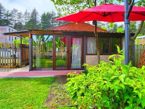 a red umbrella in front of a gazebo at House & Yard Sesil M 110m to beach in Ureki