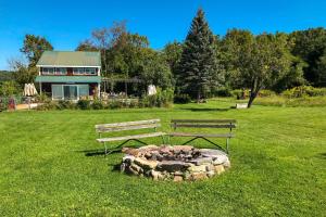 a park with two benches and a fire pit in the grass at Heart House in Gilford