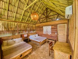 a room with two beds and a table in a straw hut at Hotel Isla Mucura in Isla Mucura