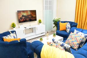 a living room with blue couches and a tv at Nomads Luxurious Homes in Nairobi