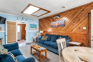 a living room with a blue couch and a wooden wall at The Blue Parrot Cottage in Ocean Beach