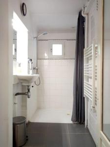 La salle de bains blanche est pourvue d'un lavabo et d'une douche. dans l'établissement House at the foot of the castle of Fougeres, à Fougères