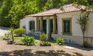 una pequeña casa blanca con puertas verdes y árboles en Quinta Das Murtas, en Sintra