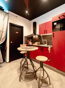 a kitchen with red cabinets and two bar stools at spa de la quarterelle LOVE ROOM 88 VOSGES in Remiremont