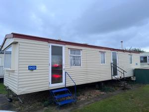 Casa móvil blanca con escalera azul y casa en S422 Golden Palm 8 Berth Caravan, en Chapel St. Leonards
