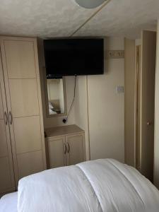 Un dormitorio con una cama con un televisor de pantalla plana en la pared. en S422 Golden Palm 8 Berth Caravan, en Chapel St. Leonards