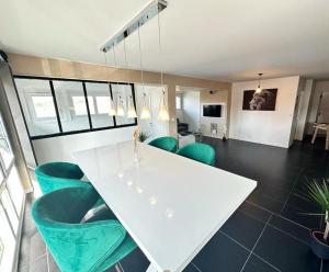 a dining room with a white table and green chairs at L'Élégant in Douvaine