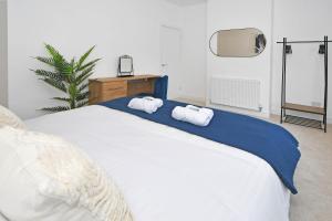 a bedroom with a large white bed with towels on it at Unity House - A Stylish Haven with 3 Bedrooms, Perfect for Your Tranquil Getaway in Crewe