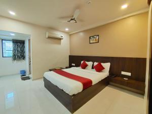 a bedroom with a large bed with red pillows at Hotel Palav Palace in Ahmedabad
