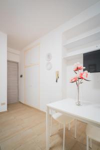 代森扎諾－德爾加達的住宿－Suite "Castello" del Garda - APT per coppie Garda，白色的用餐室配有白色的桌子和粉红色的鲜花