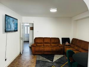 a living room with a brown leather couch at Liberty Inn Room with sharing toilet and kitchen in Liverpool