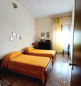a bedroom with two beds and a window and a chair at Casa Vacanze Sa Rocca Tunda- Putzu idu- sardegna in Putzu Idu