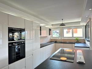a kitchen with white cabinets and black appliances at L'Élégant in Douvaine