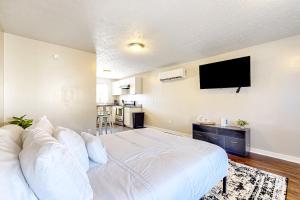 1 dormitorio con 1 cama blanca y TV de pantalla plana en Ambry On Central, en La Follette