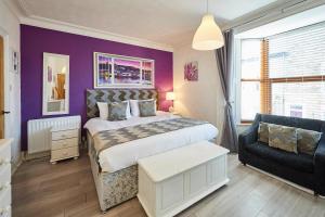sypialnia z fioletowymi ścianami, łóżkiem i kanapą w obiekcie Host & Stay - George House w mieście Whitby