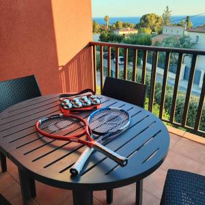 una mesa con raquetas de tenis y pelotas en el balcón en Studio vue mer, en Bandol