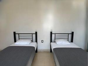 - deux lits assis l'un à côté de l'autre dans une pièce dans l'établissement Hostal Andaina, à Oaxaca