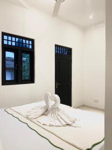a white room with a swan sculpture on a bed at Changami Residence in Nugegoda