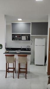 una cucina con frigorifero, tavolo e sedie di JARDIM DAS PALMEIRAS II - HOME RESORT a Ubatuba