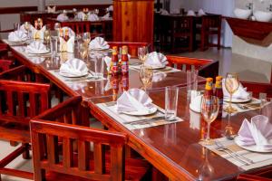 HADJENS HOTEL في موانزا: طاولة خشبية طويلة مع كراسي وكاسات للنبيذ