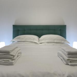 a bed with white pillows and a green headboard at MILA by The Blue Twins apartments Milano in Milan