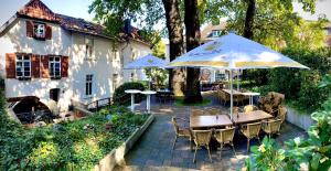 a patio with tables and umbrellas in front of a house at Historischer Gasthof Kaisermühle - Hotel & Restaurant Viersen Zentrum in Viersen