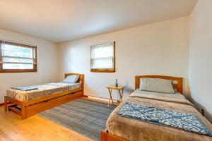 1 dormitorio con 2 camas, mesa y 2 ventanas en South Burlington Home with Seasonal Pool!, en South Burlington