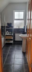 baño con lavabo, bañera y ventana en Bernie’s Place, en Ballyliffin