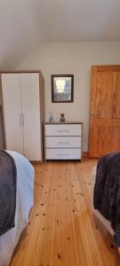 a bedroom with two beds and a dresser and a wooden floor at Bernie’s Place in Ballyliffin