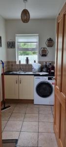 a kitchen with a washing machine and a window at Bernie’s Place in Ballyliffin