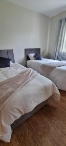 two beds in a hotel room with white sheets at Bernie’s Place in Ballyliffin
