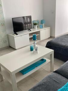 a living room with a white coffee table and a tv at Radazul Vibes by Agüita Salada Suites in Radazul
