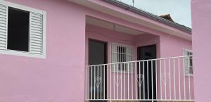 a pink house with a white balcony at Pousada Aquarela in São Thomé das Letras