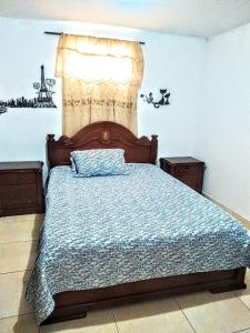 a bedroom with a bed with a blue comforter and a window at My second house in Manizales