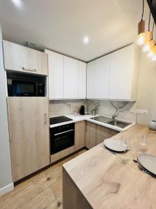 Una cocina con gabinetes blancos y un refrigerador negro. en Scorfel Lodge, Maison bleue, Terrasse, 1km mer, en Trégastel