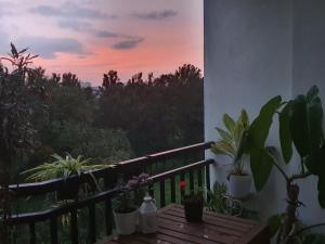 a balcony with a wooden table with plants and a sunset at Serene Home Stay in Bangalore