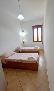 two beds in a small room with a window at Villa Cecita Holiday in Sellia Marina