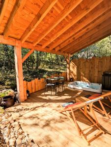 Aux Trois Chênes Lodge Spa في ميرْكو: جناح خشبي مع طاولة وكراسي على سطح