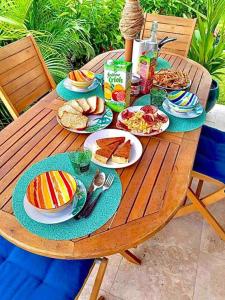 uma mesa de madeira com pratos de comida em Duplex Green Paradise , piscine , accès mer 5mn em Le Diamant