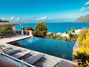 uma piscina com cadeiras e o oceano ao fundo em Duplex Green Paradise , piscine , accès mer 5mn em Le Diamant