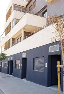 un edificio azul con dos puertas de garaje frente a un edificio en Urbanlux Olimpia Sleep & More en Albacete